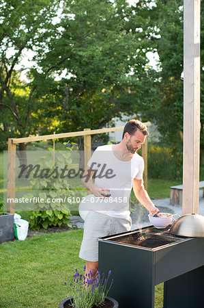 Man having grill in garden, Stockholm, Sweden