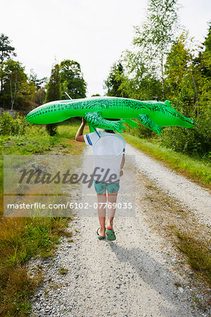 Boy walking with inflatable crocodile