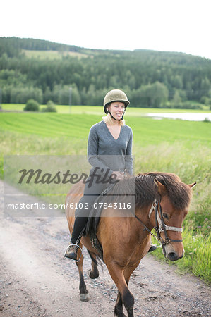 Smiling mid adult woman riding on horse