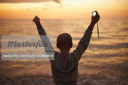 Boy holding camera at sea