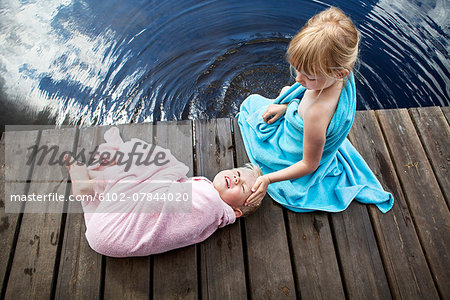 Brother and sister wrapped in towels on jetty