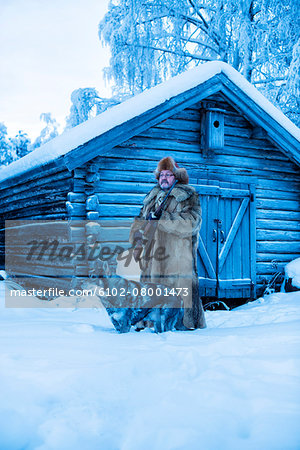 Mature man in front of log house