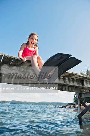 Happy girl wearing flippers on jetty