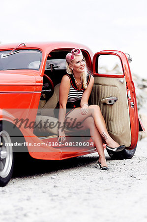 Woman wearing retro clothes sitting in vintage car