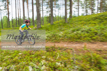 Boy cycling through forest