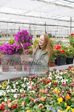 Smiling teenage girl in garden center choosing plants