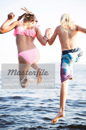 Boy and girl jumping into water