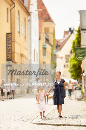 Mother with daughter walking on cobbled street