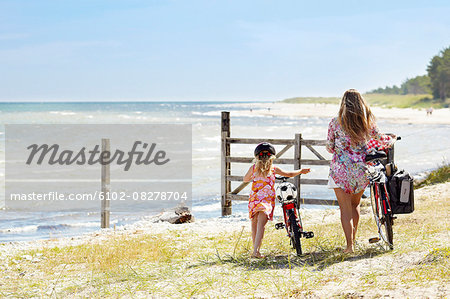 Mother with daughter with bicycles at sea