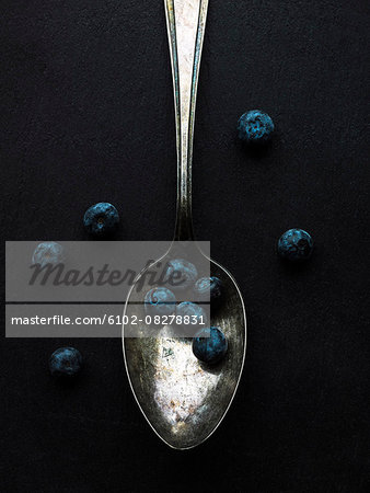 Blueberries and spoon on black background