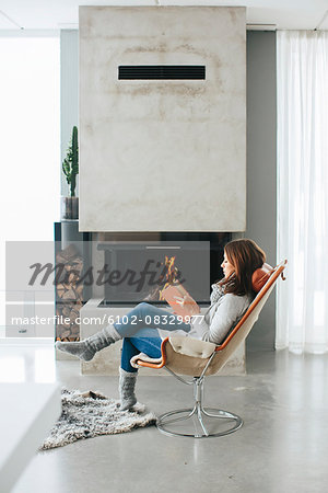 Woman reading book in front of fireplace