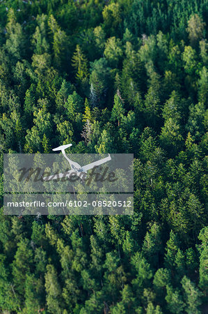 Aerial view of glider flying above forest