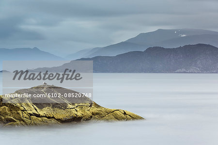 Sea with mountain range on cloudy day