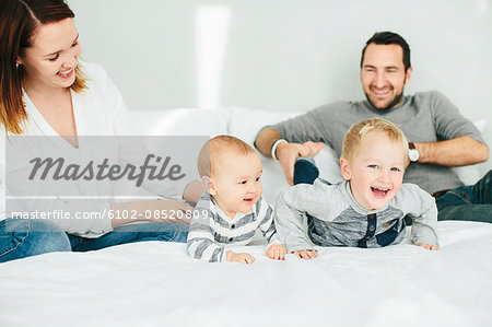 Parents with two small kids playing in bedroom