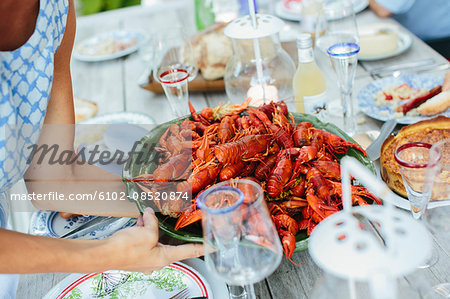 Mature woman placing bowl of crayfish on table