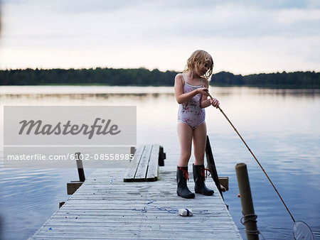 Two young girls standing on jetty, fishing using fishing rods, Stock Photo,  Picture And Royalty Free Image. Pic. ISO-IS09B8K5F