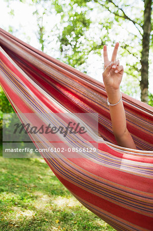 Girl resting in hammock and showing peace sign