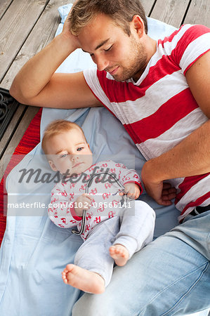 Father and baby lying on jetty