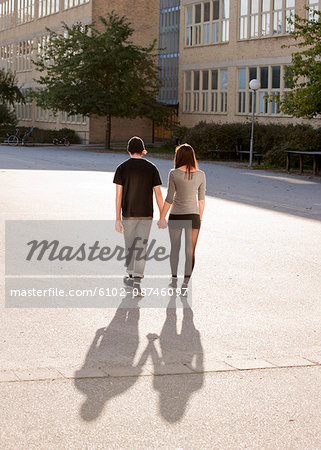 Teenage couple walking through school yard