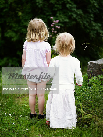 Two girls standing in garden, rear view