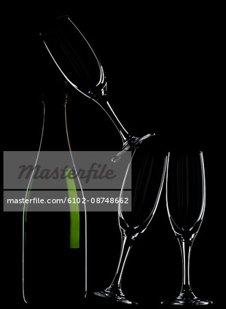 Champagne bottle and glasses against black background
