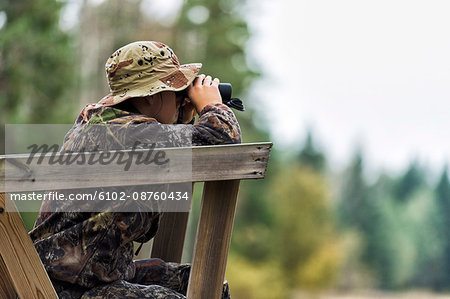 Teenager with binoculars on hunting tower
