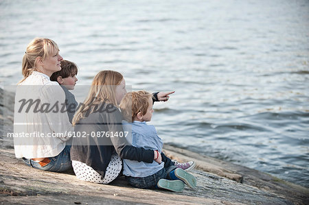 Mother with three children sitting at water, Nacka, Sweden