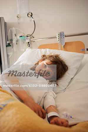 Girl lying on hospital bed with IV drip on arm