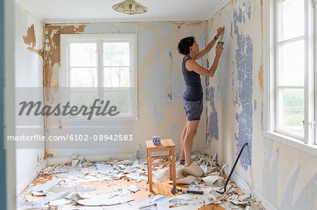 Woman renovating room and removing wallpaper