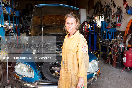 Woman mechanic repairing vintage car