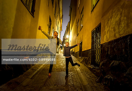 Mother with son jumping on street