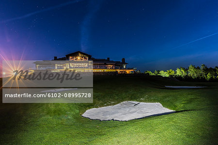 Golf course, illuminated building on background