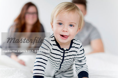 Baby in bed, parents on background