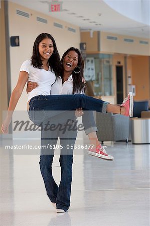 Female student carrying his friend and smiling