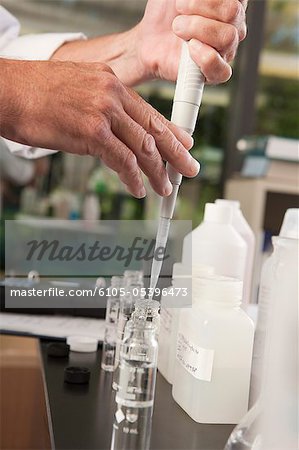 Scientist using a calibrated pipette with sample bottles in the laboratory of water treatment plant