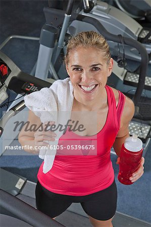 Woman standing on a treadmill and drinking water