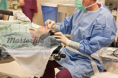 Ophthalmologist taking drape off eye and cleaning up patient after surgery