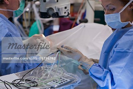 Surgical technologist passing a phaco hand piece to doctor during cataract surgery