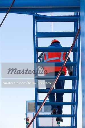 Engineer on upper staircase of industrial plant