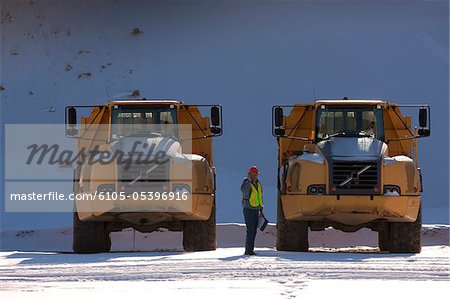 Engineer on phone during inspection of earth movers at a construction site