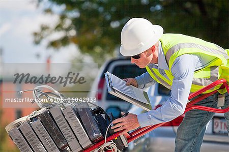 Cable installer with hand truck full of set-top boxes reading work orders