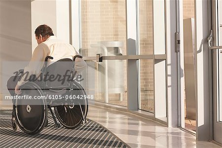 Businessman with spinal cord injury in wheelchair in a office building entrance