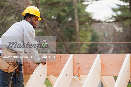 Carpenter using a snap line on beam