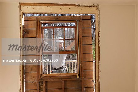 Hispanic carpenter removing newly cut door access to deck on home