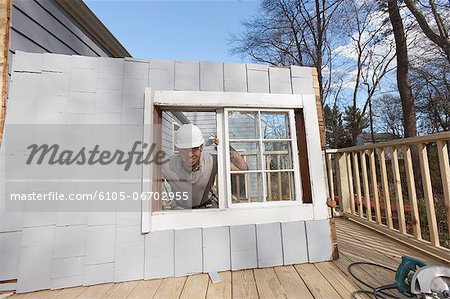 Hispanic carpenter removing newly cut door access to deck on home