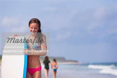 Happy girl with surfboard on the beach, Block Island, Rhode Island, USA