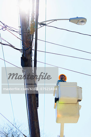 Power engineer riding in lift bucket to work on power lines, Braintree, Massachusetts, USA