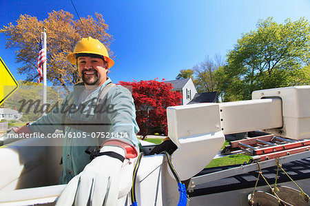 Power engineer in lift bucket with safety equipment for power lines at truck level