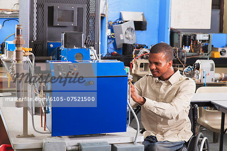 Student in wheelchair studying natural gas fuel line on furnace in HVAC classroom