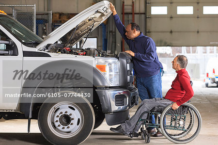 Automotive maintenance technician and supervisor with spinal cord injury in truck garage